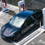 Czarna Tesla podłączona do ładowarki przy miejskim parkingu garażowym