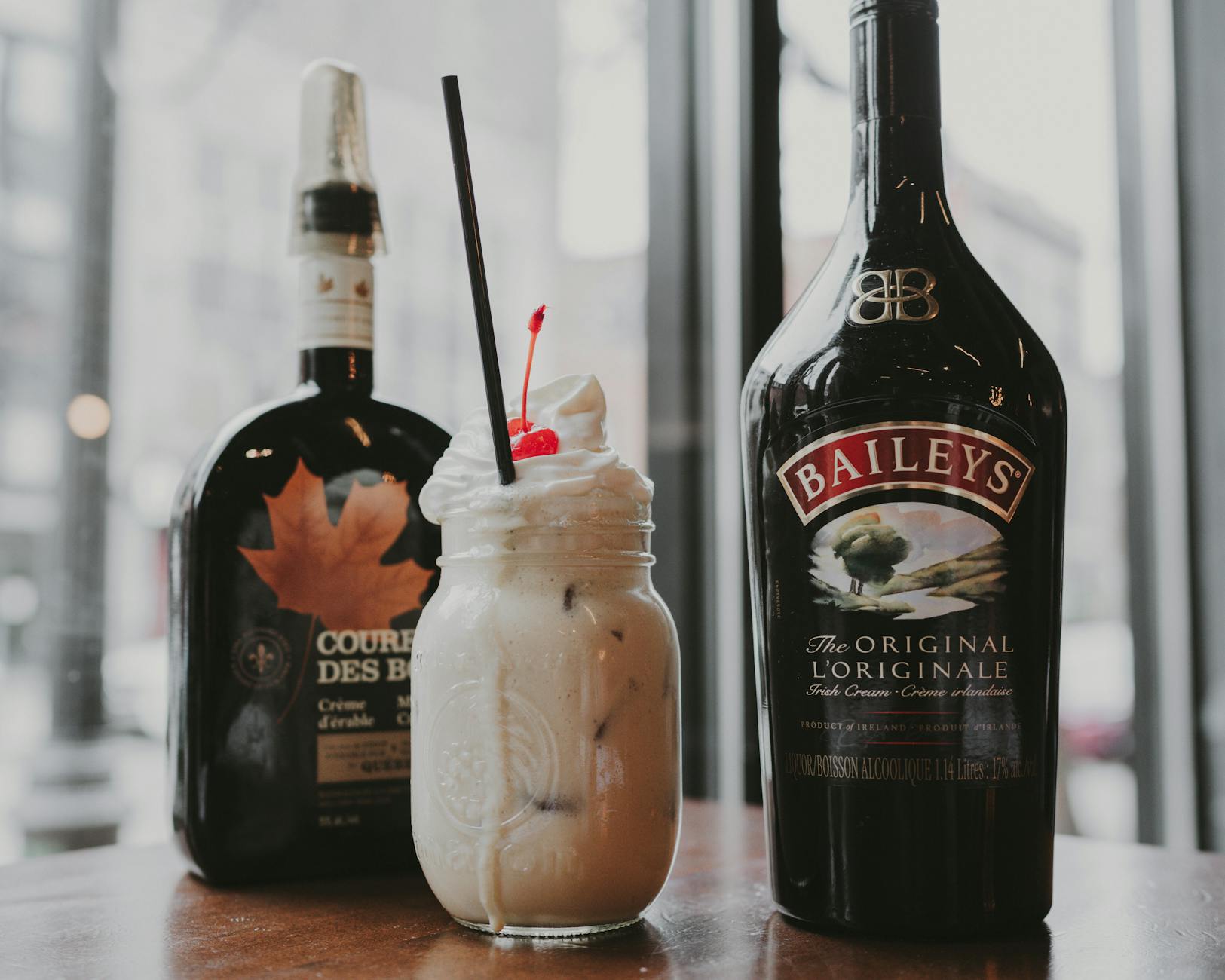 Kremowy drink typu Baileys z wisienką w przytulnym, domowym wnętrzu