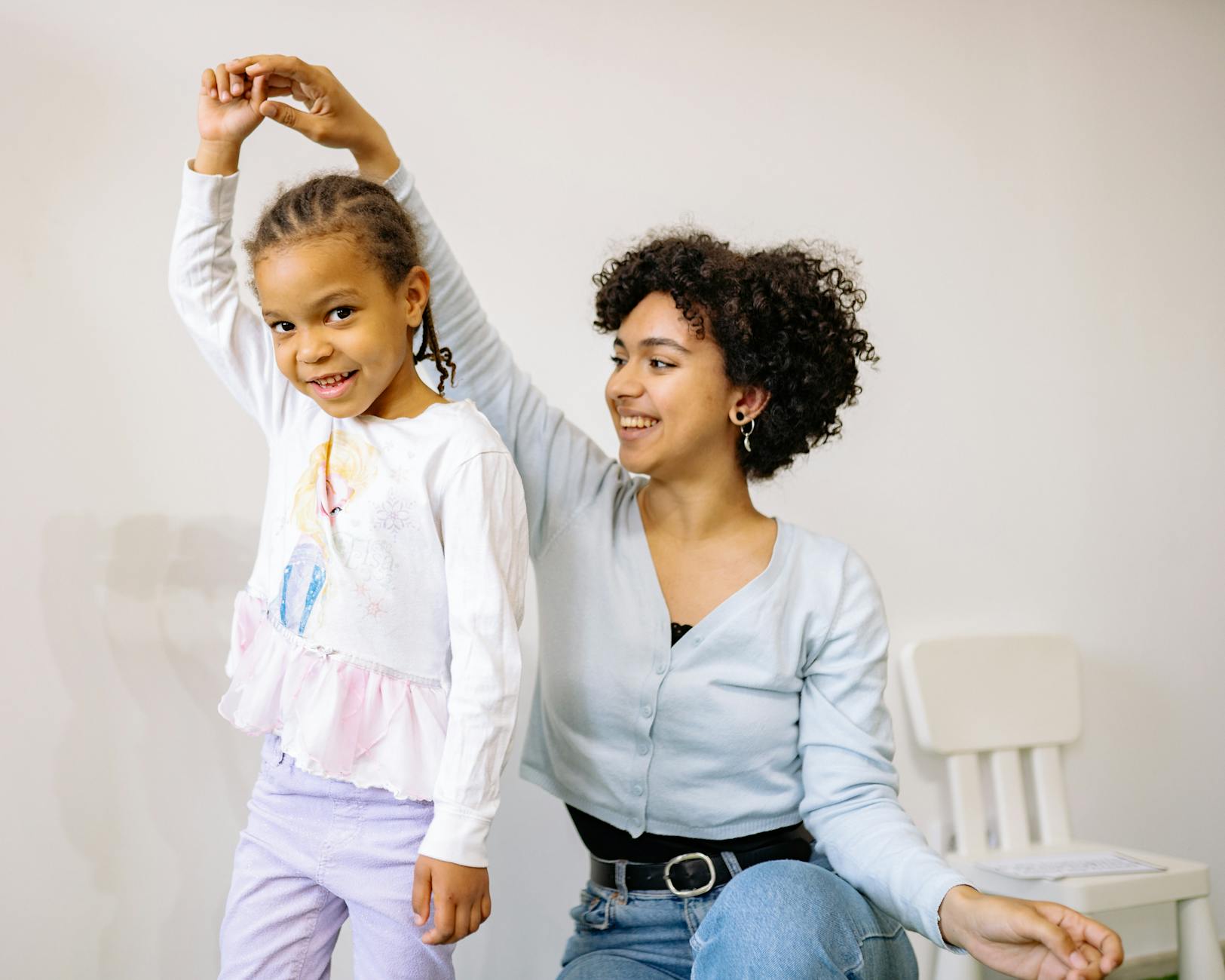 Uśmiechnięta mama przytula córkę w domu przed pójściem do przedszkola