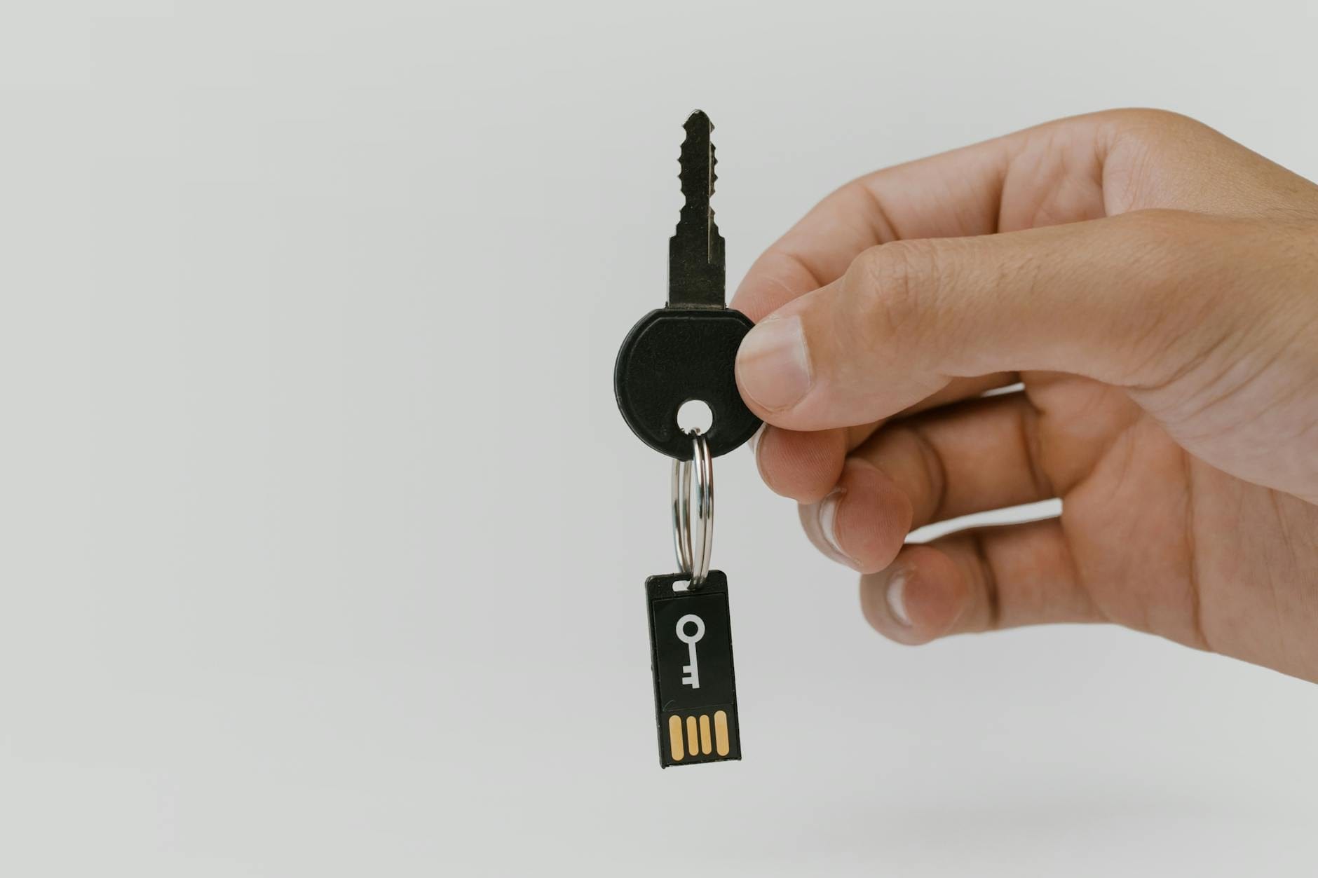 Dłoń trzymająca klucz z pendrive’em jako symbol bezpieczeństwa danych