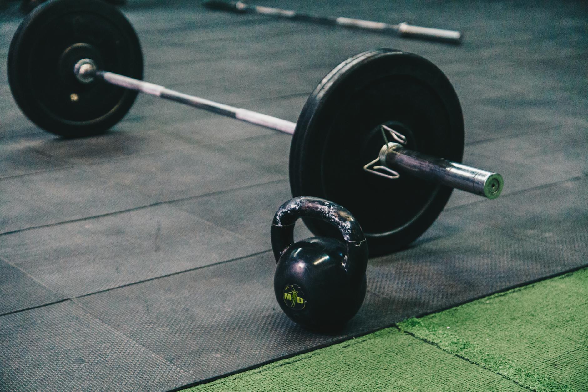 Sztanga i kettlebell leżące na podłodze siłowni