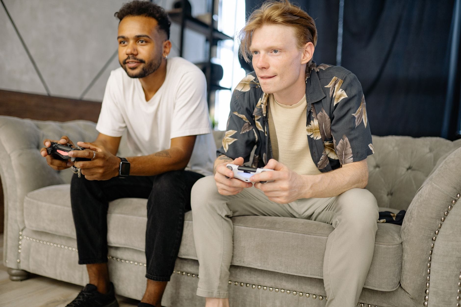 Dwóch przyjaciół gra razem na PS4 na kanapie w salonie
