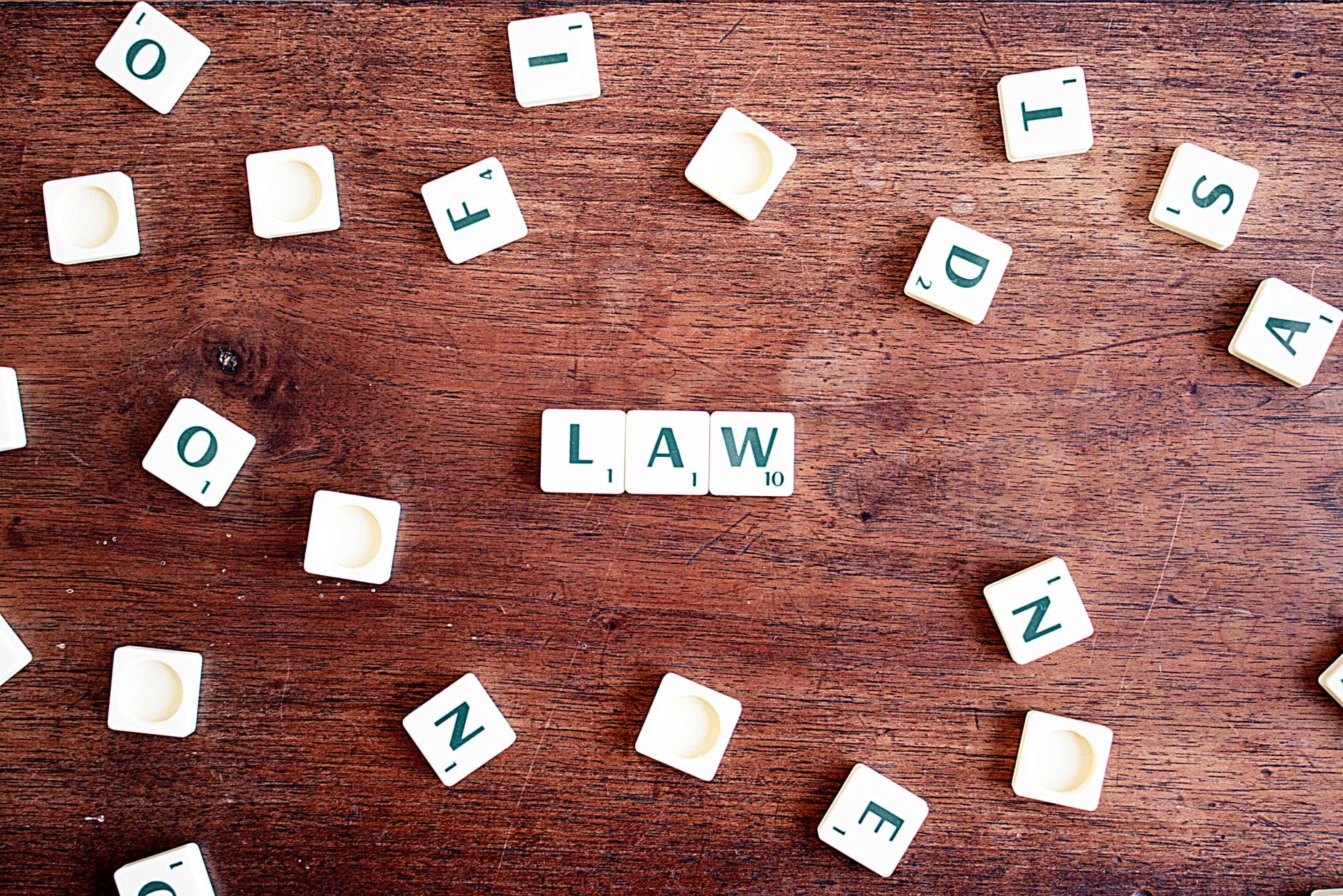 Kafelki Scrabble układające się w napis LAW na drewnianym stole