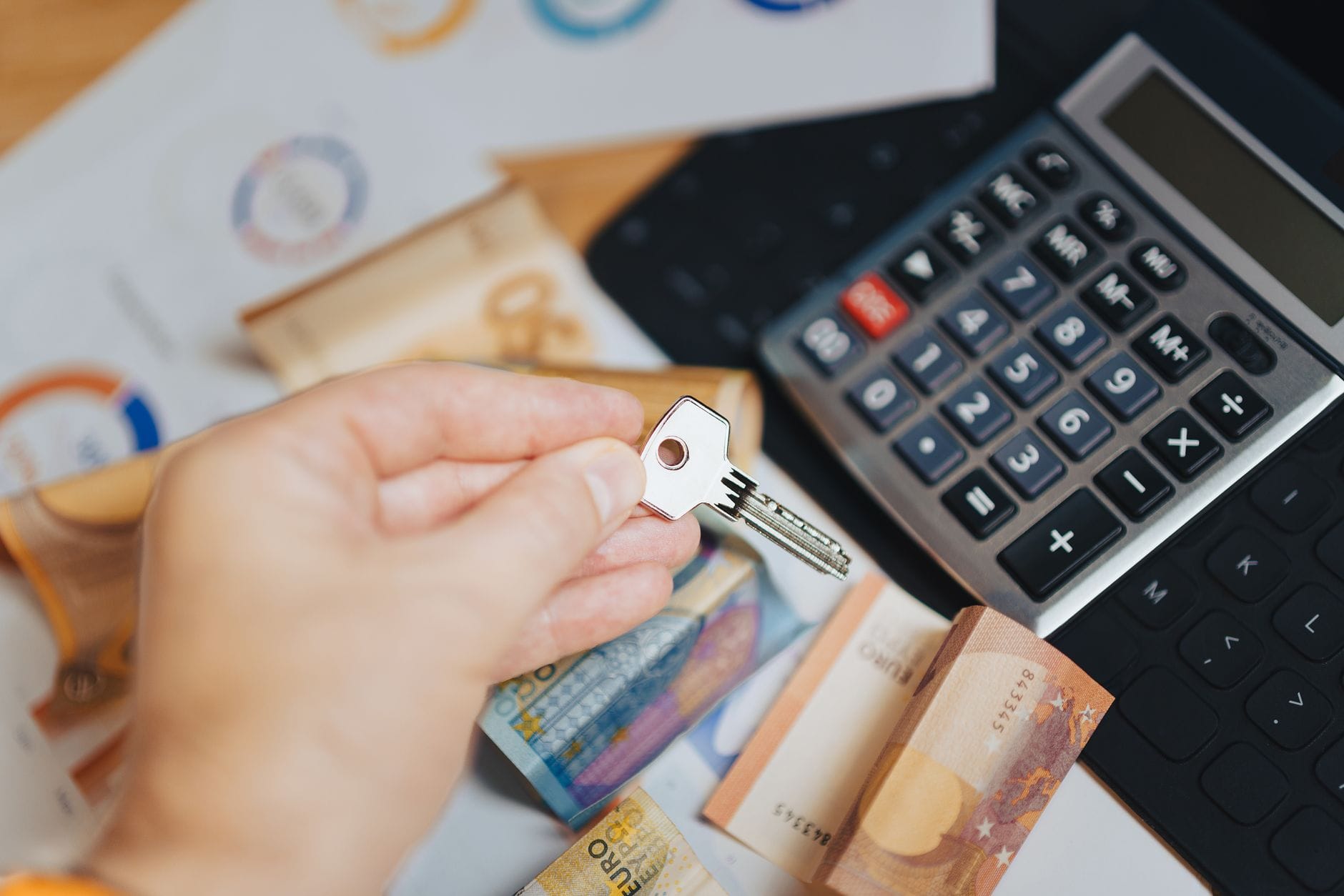 Dłoń trzyma klucz nad banknotami euro i kalkulatorem, symbol finansowania
