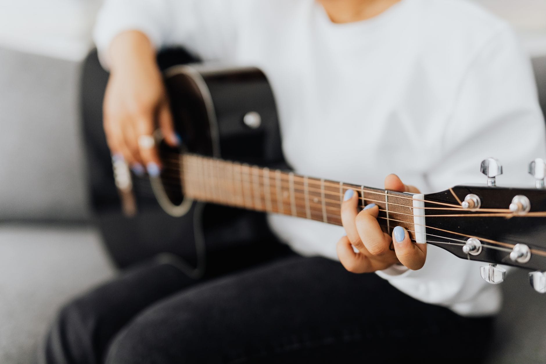 Dłoń początkującego gitarzysty na gryfie akustycznej gitary