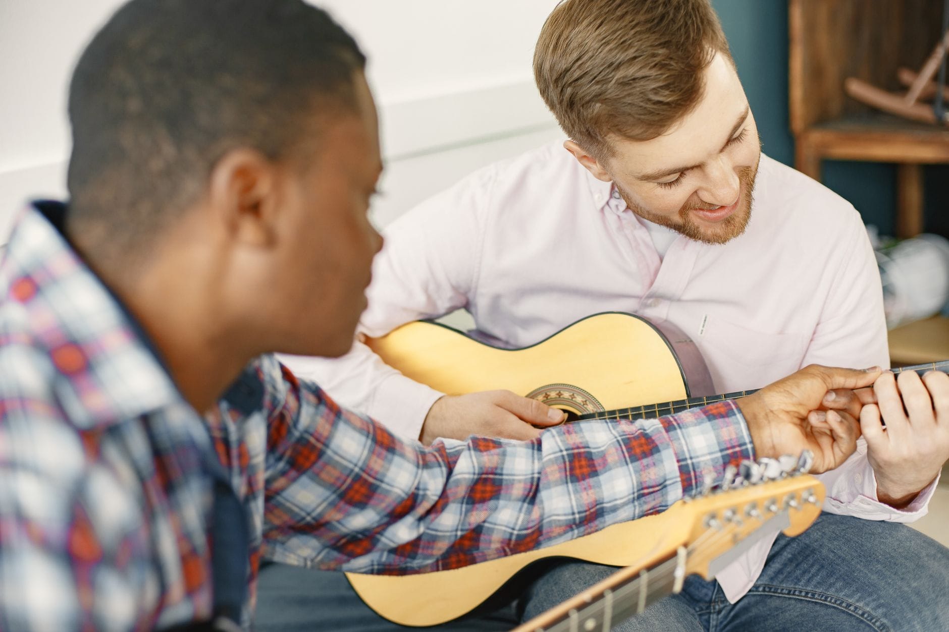 Nauczyciel i uczeń podczas lekcji gry na gitarze w pomieszczeniu