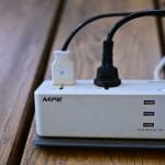 Listwa zasilająca z portami USB i podłączonymi kablami na biurku