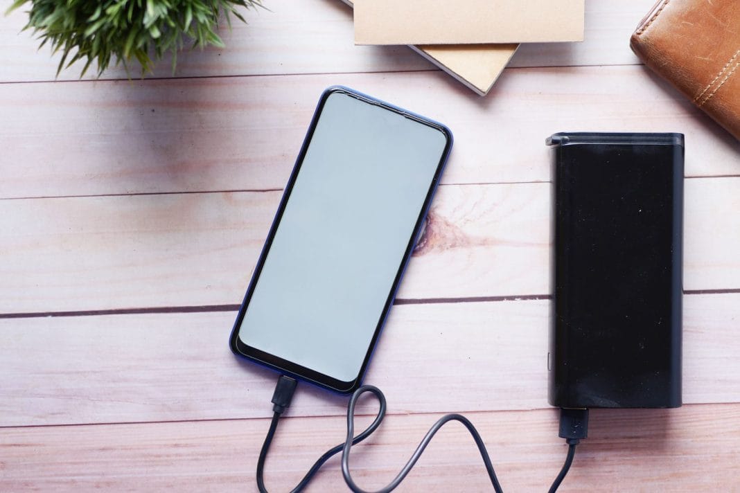 Smartfon ładowany powerbankiem na drewnianym biurku