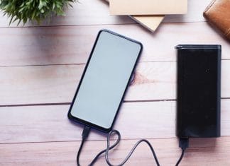 Smartfon ładowany powerbankiem na drewnianym biurku